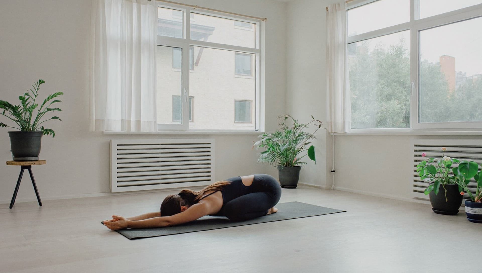 Woman resting in child’s pose on a yoga mat in a bright room